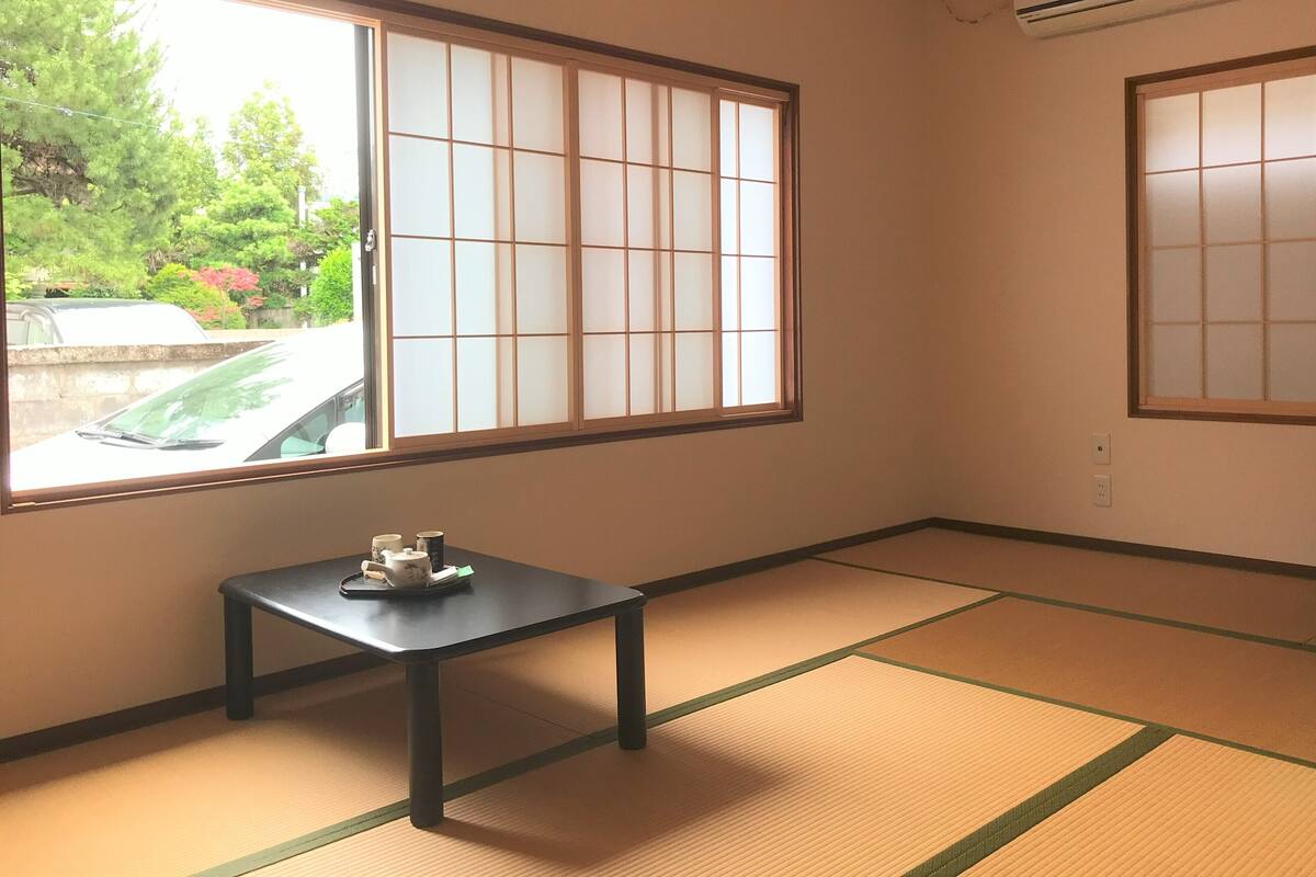 Um quarto com piso de tatame, uma mesa baixa com chá e grandes biombos shoji.