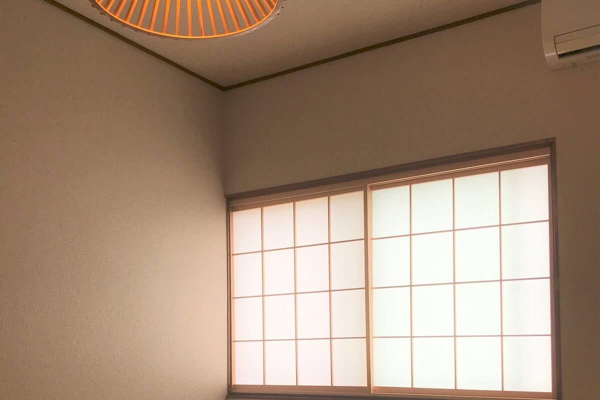 Quarto com piso de tatame, janela com tela tipo shoji e luminária no teto.