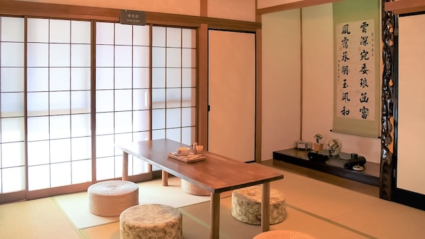 A traditional Japanese room with tatami flooring, a low table, and cushions. - Guesthouse Hakuka - Hostel (Kanazawa)