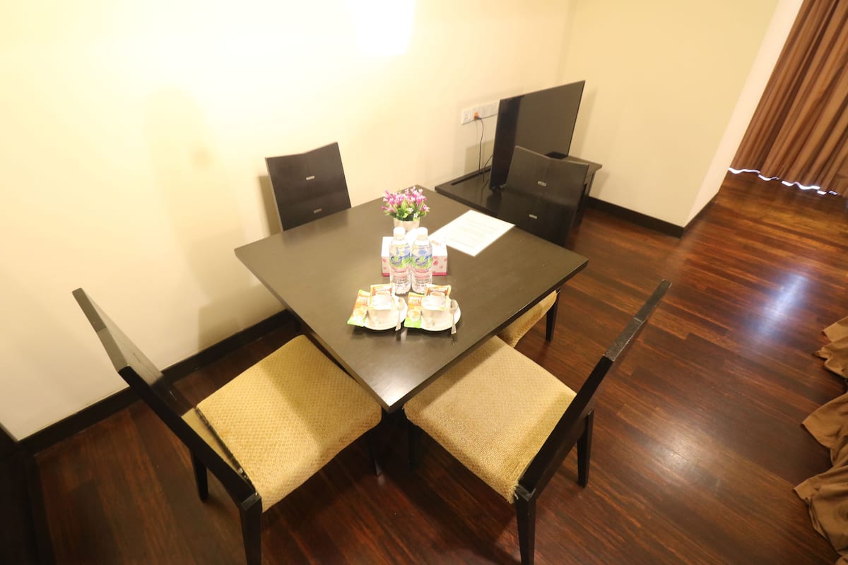 Une table à manger avec quatre chaises, un vase rempli de fleurs et un menu posé sur la table.