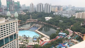 A high-rise hotel with a pool and water park, surrounded by greenery and other buildings. - Raintree Resort suites at Bandar Sunway (Petaling Jaya)