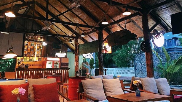 Un restaurante con mobiliario de madera, una zona de bar y vistas al exterior.