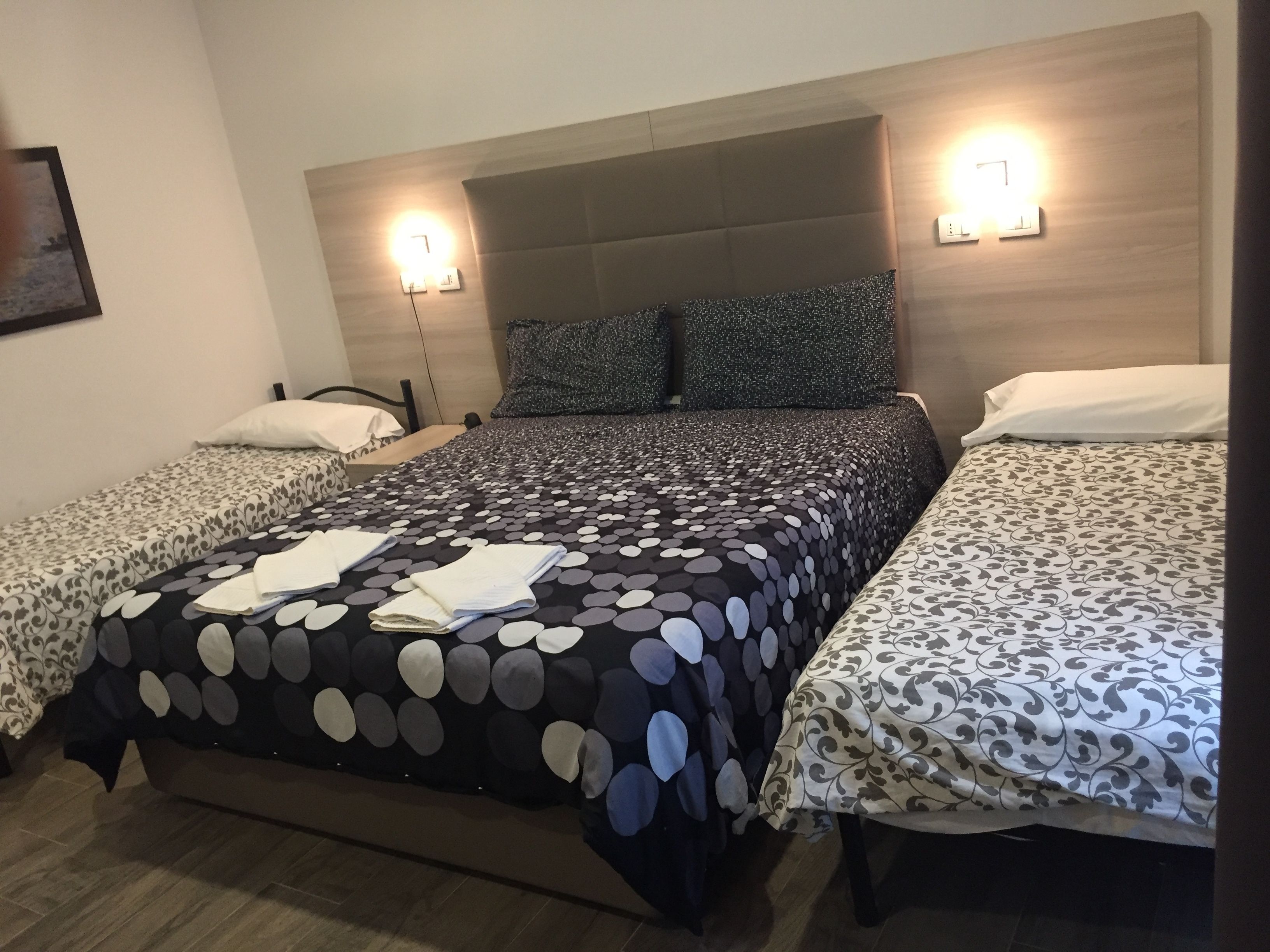 A hotel room with a large bed, two bedside tables, and two wall-mounted lights.