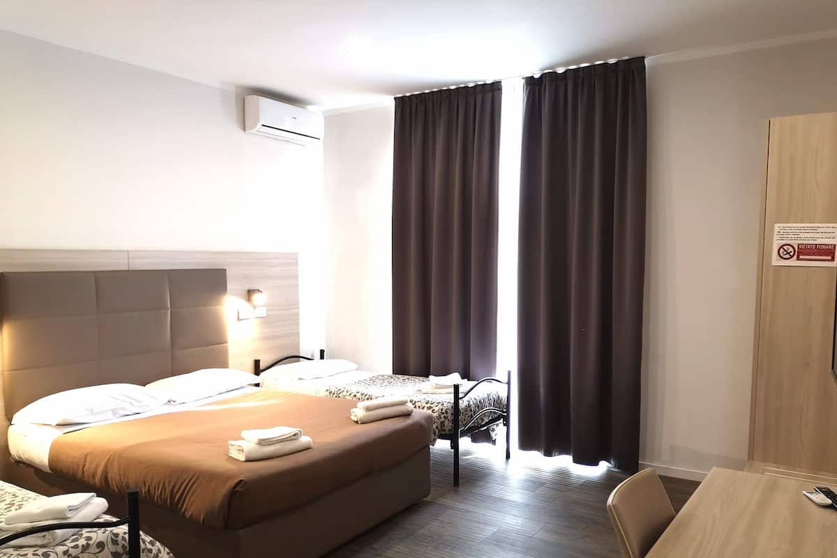 A hotel room with two beds, a desk, and a chair.