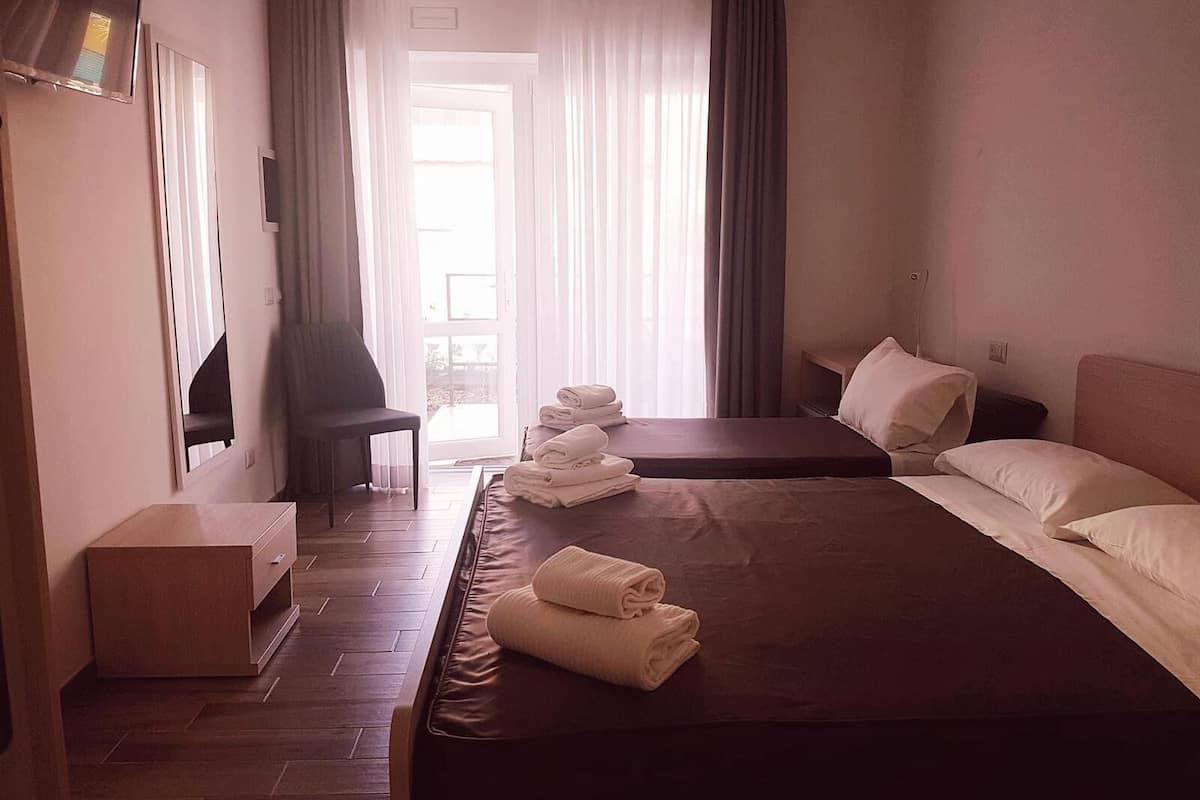 A hotel room with a large bed, a chair, a desk, and a view of the outdoors.