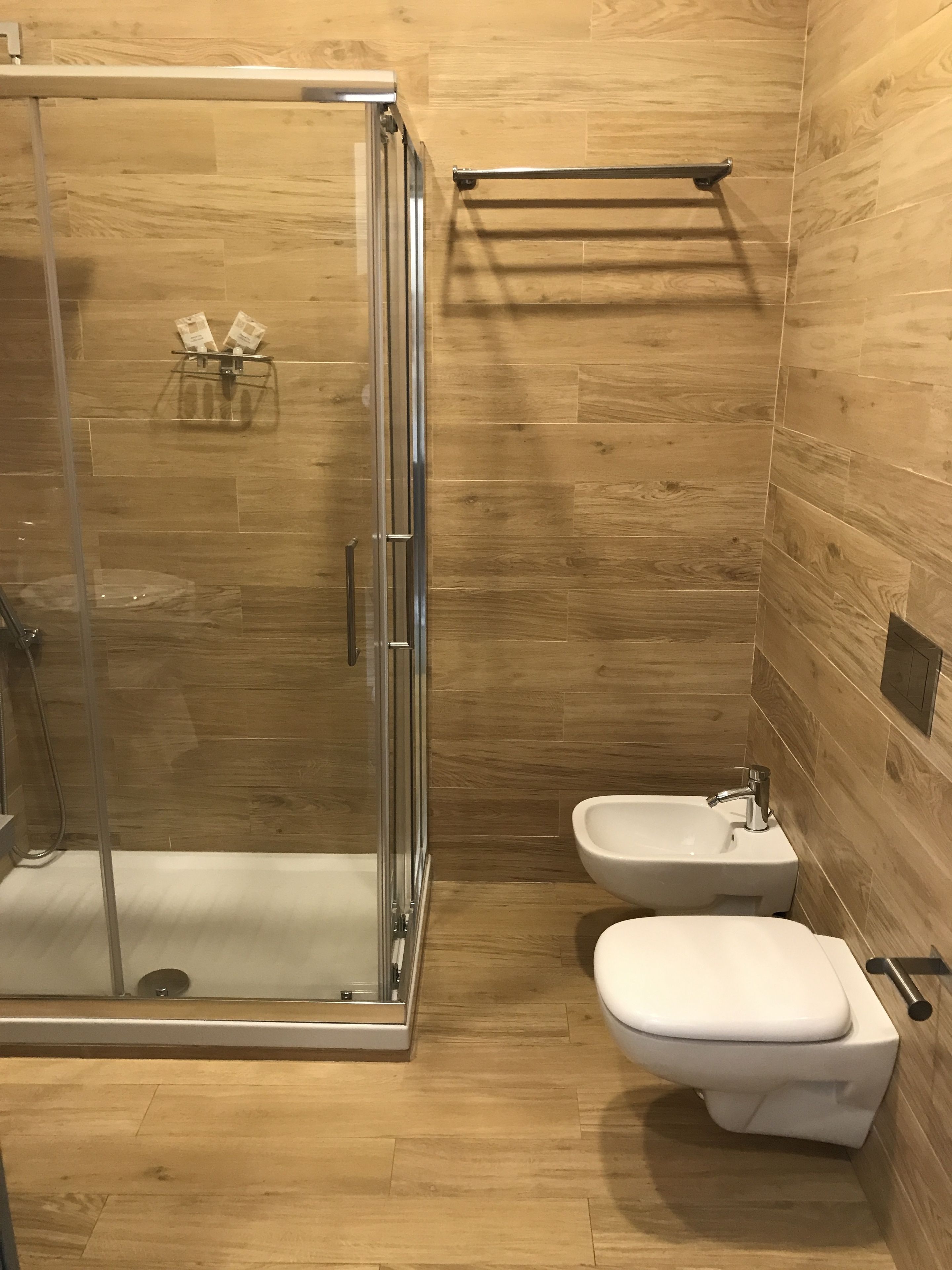A modern bathroom with a glass-enclosed shower, a toilet, and a bidet.