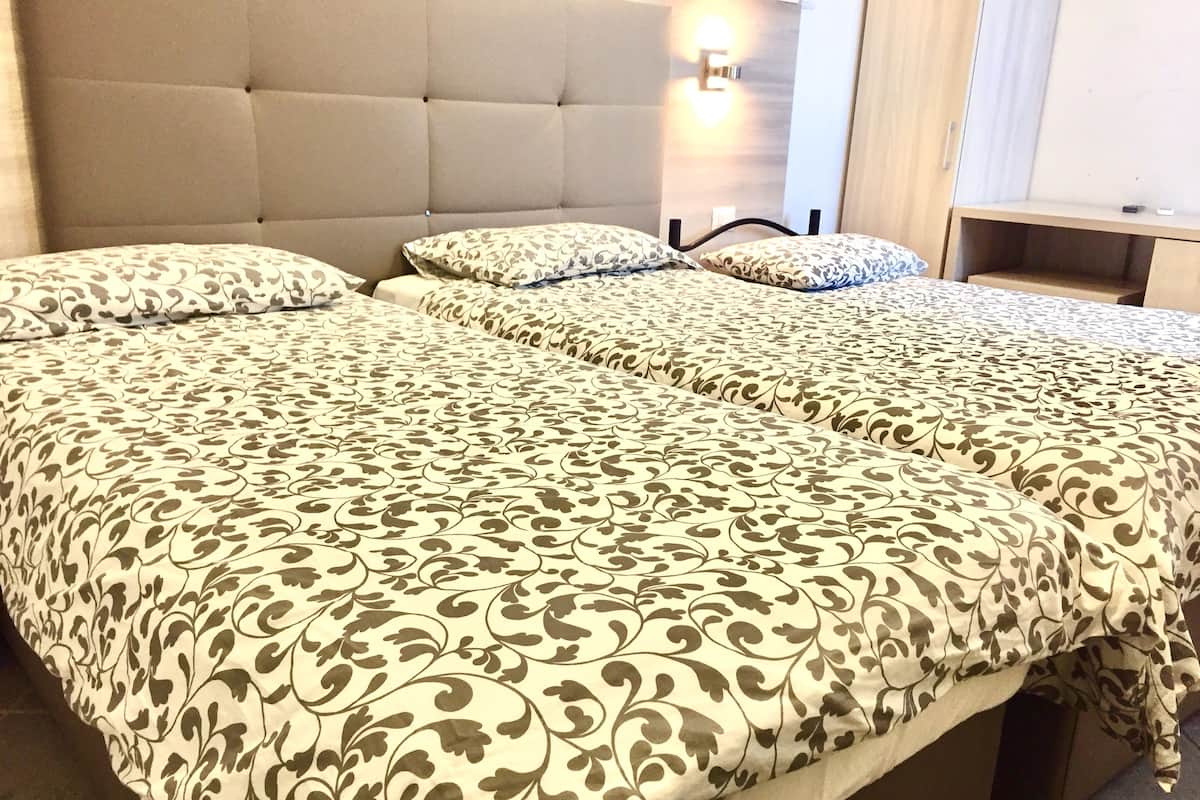 A double bed with a patterned bedspread and two pillows, a tufted headboard, and a bedside table with a lamp.