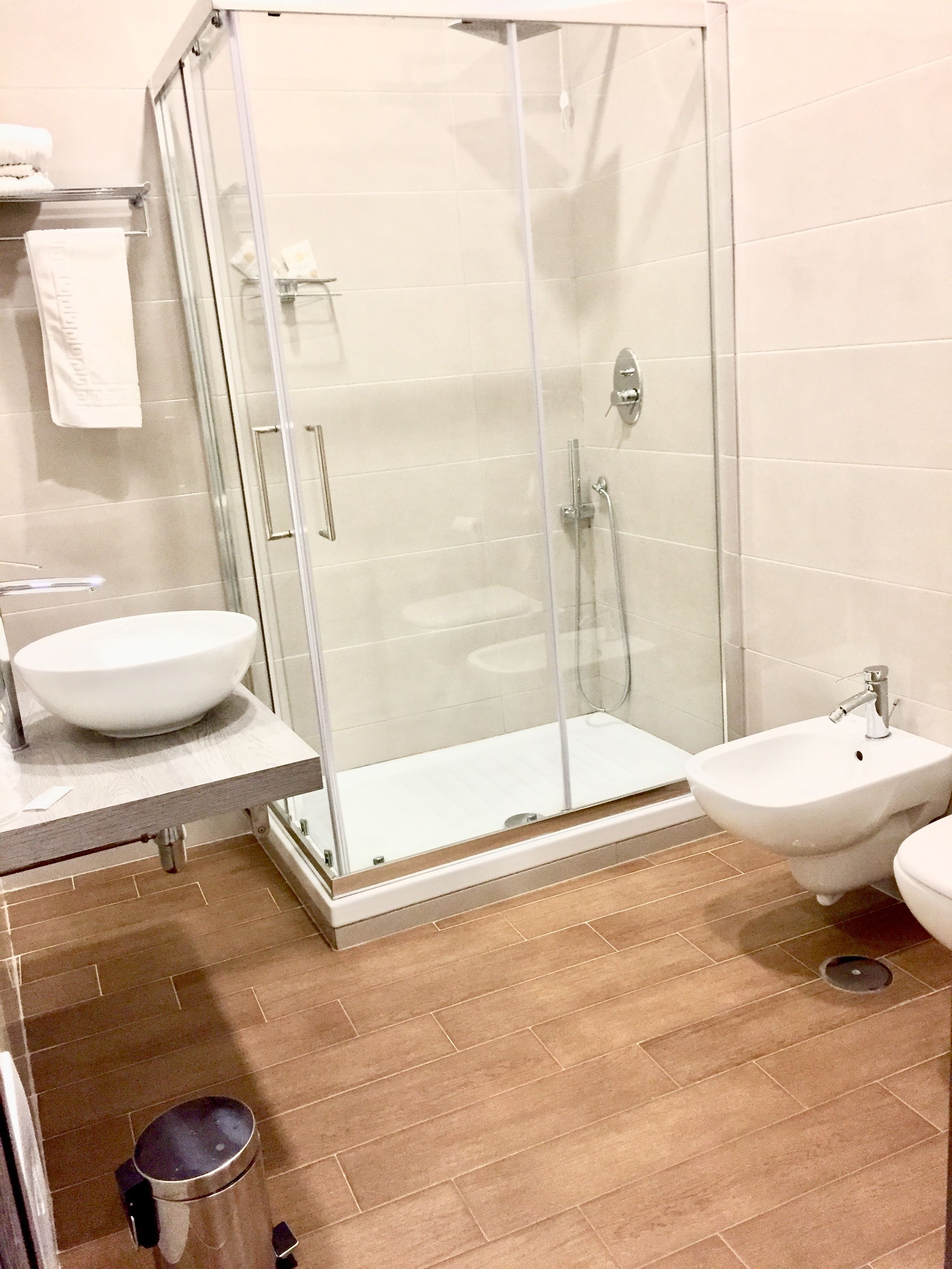 A modern bathroom with a glass-enclosed shower, a sink, and a bidet.