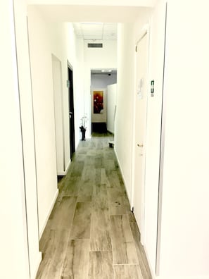 A narrow hallway with white walls and a tiled floor. There is a door on the left and a door on the right. - Hotel Academy (Fiumicino)