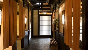 A traditional Japanese interior with tatami flooring, sliding doors, and a wooden bench. - Gokuraku Onsen Takumi No Yado (Takaharu)