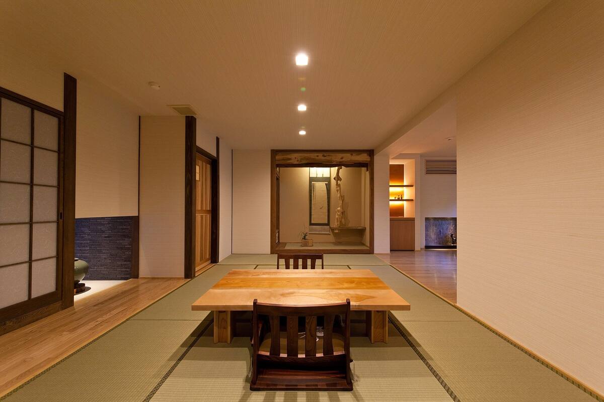 A traditional Japanese room with tatami flooring, a wooden table, and a sliding door.