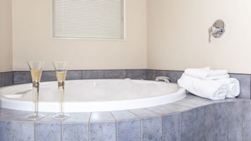 Un baño con una bañera grande, dos copas de champán y una pila de toallas blancas.