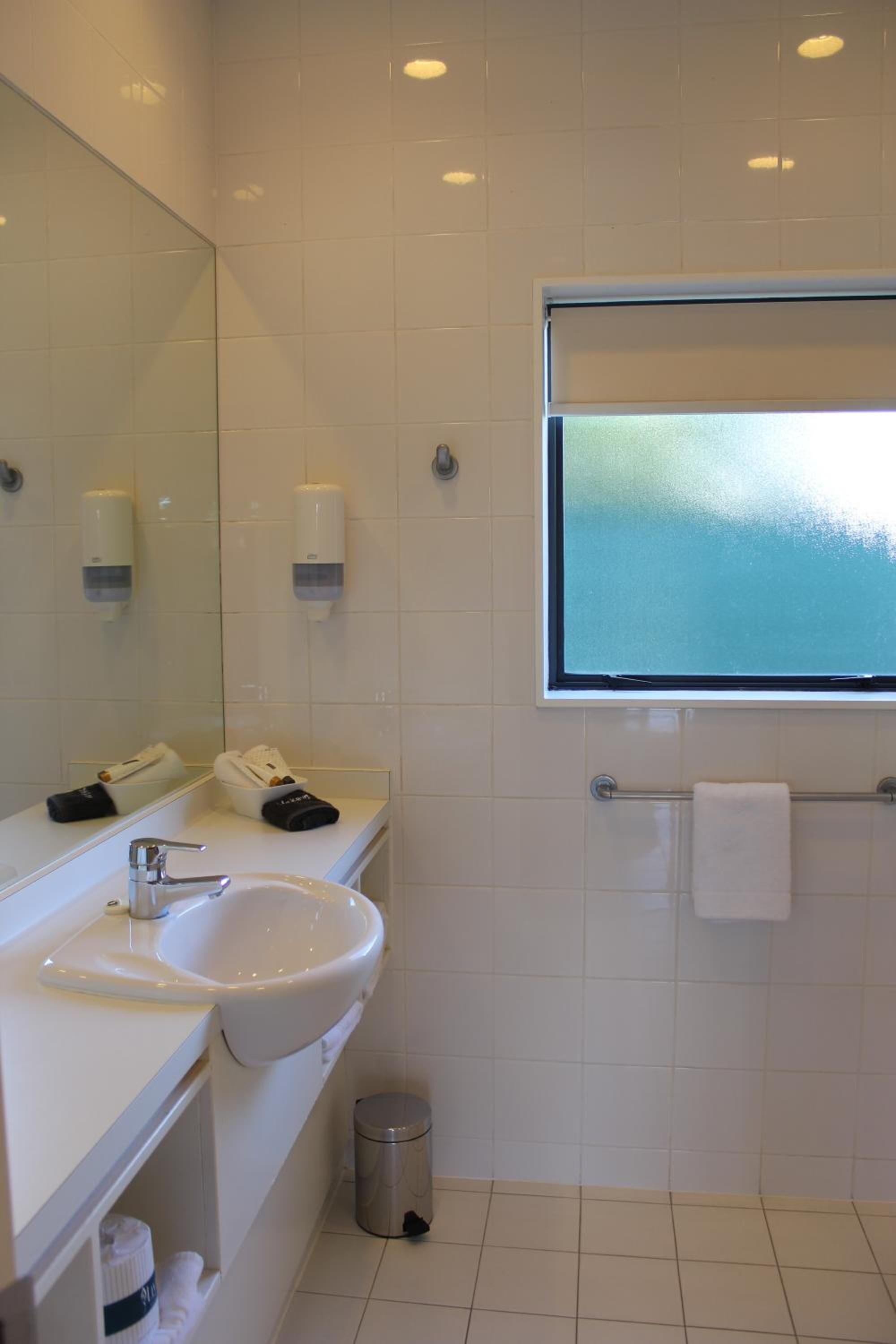 A bathroom with a white sink, mirror, and towel rack.