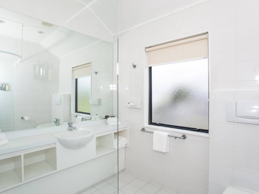 Casa de banho moderna com um espelho grande, loiças brancas e janela com vista difusa.