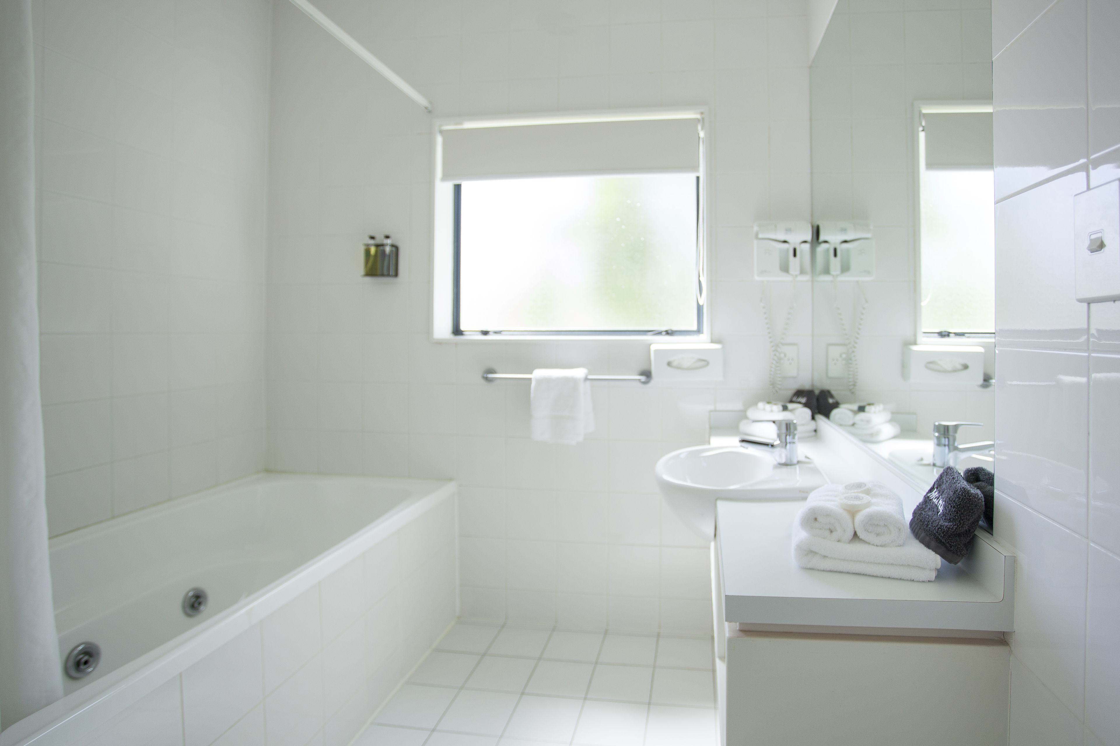 A modern bathroom with a bathtub, a sink, and a mirror.