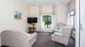 Una sala de estar con un sofá, un sillón y un televisor sobre un mueble bajo.