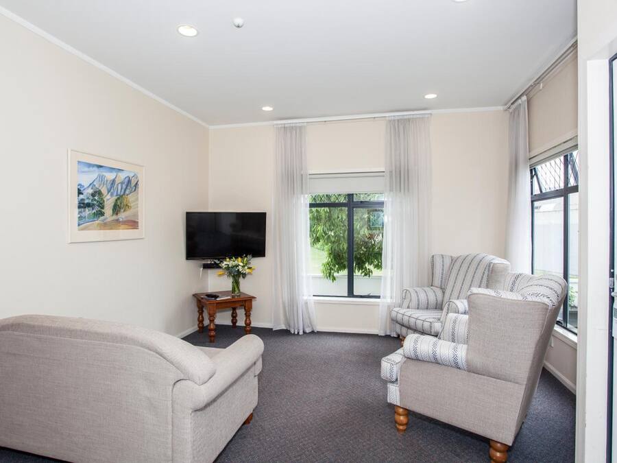 A living room with a sofa, armchair, and a TV on a stand.