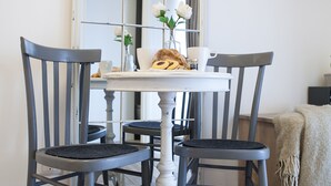 A dining table with two chairs, a mirror, and a small vase with flowers.