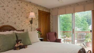 A bedroom with a bed, a chair, a lamp, and a view of the outdoors.