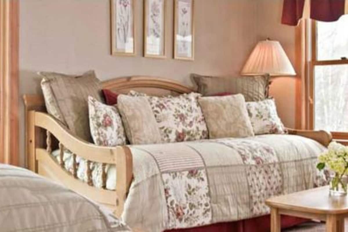 A bedroom with a wooden bed, floral bedding, a bedside table, and a window with a view.