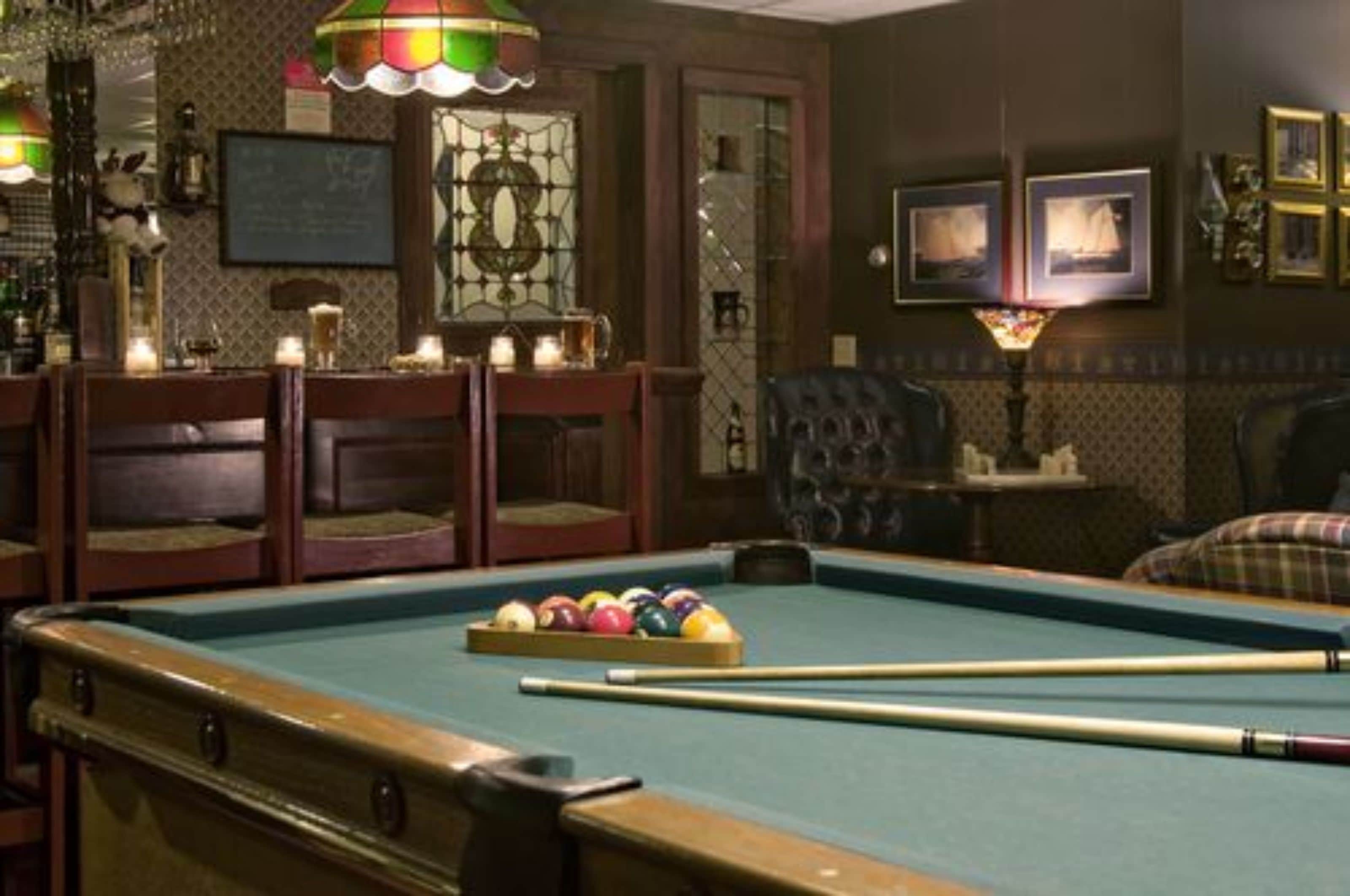 A pool table with balls, a billiard cue, and a green felt surface.