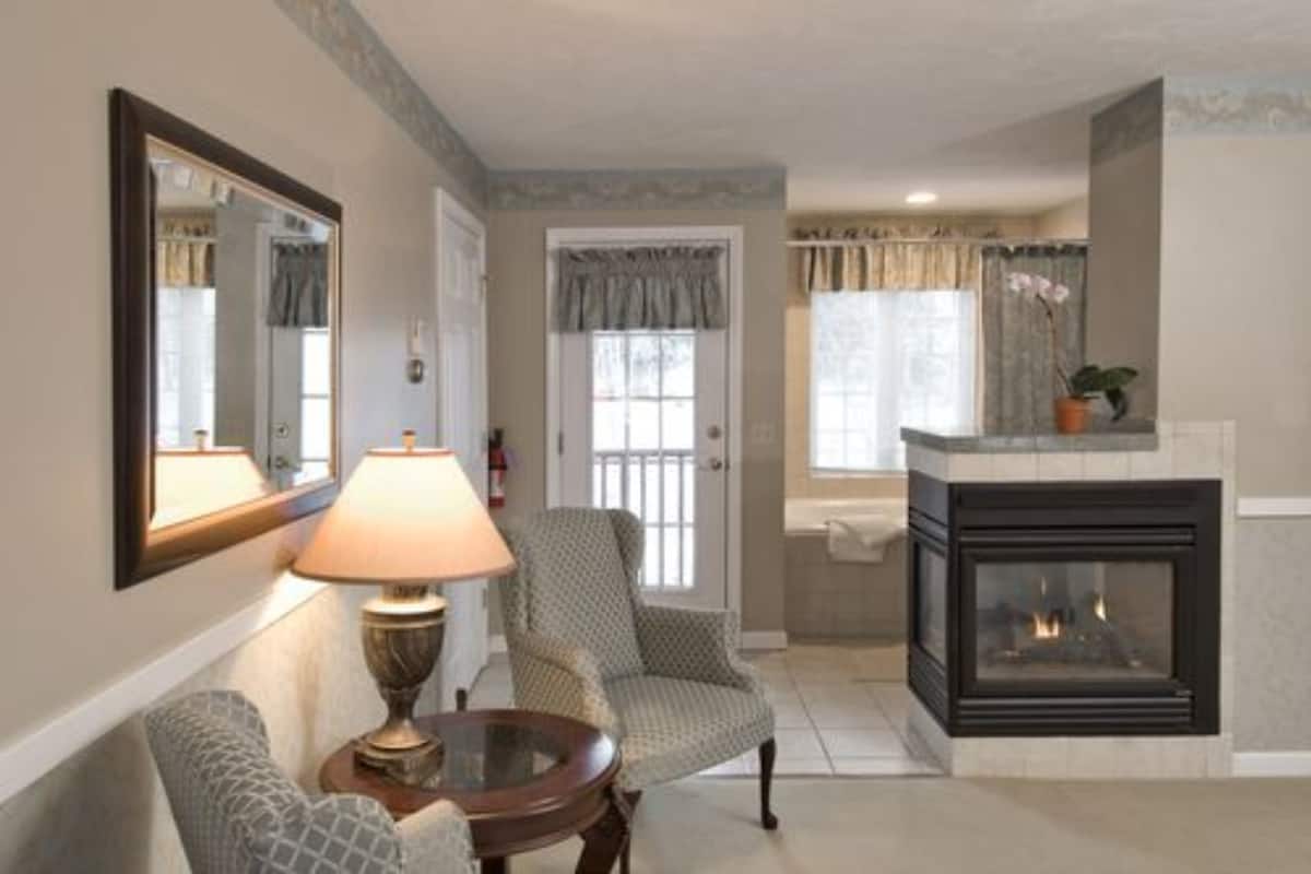 A living room with a fireplace, a lamp, a chair, and a mirror.