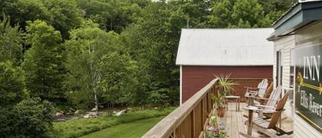 A wooden deck with outdoor seating and a view of a forested area.
