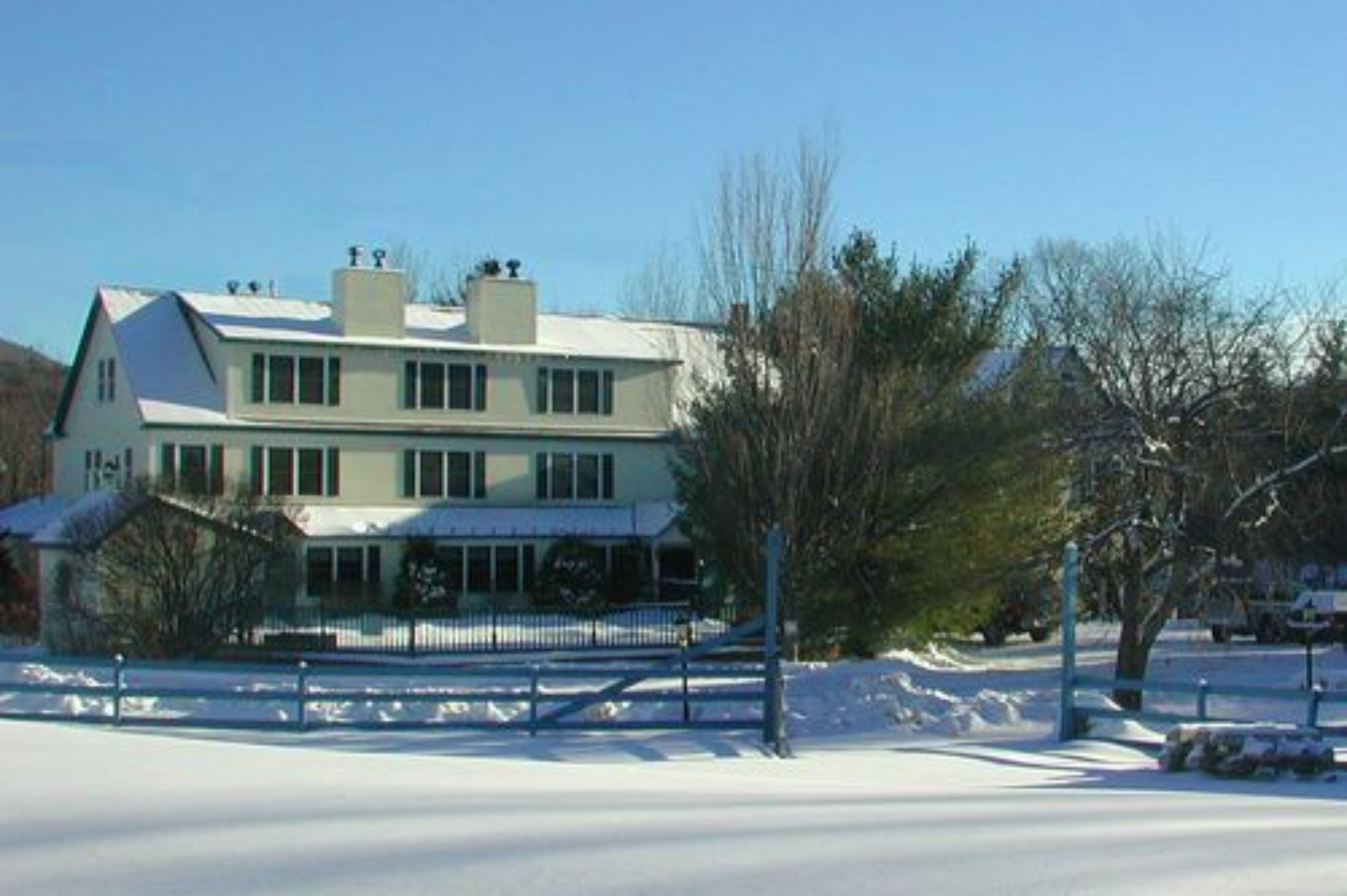 A two-story house with a covered porch and a fenced yard.