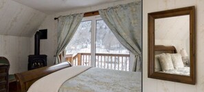 A bedroom with a large bed, a wooden headboard, a dresser, a mirror, and a window with curtains.