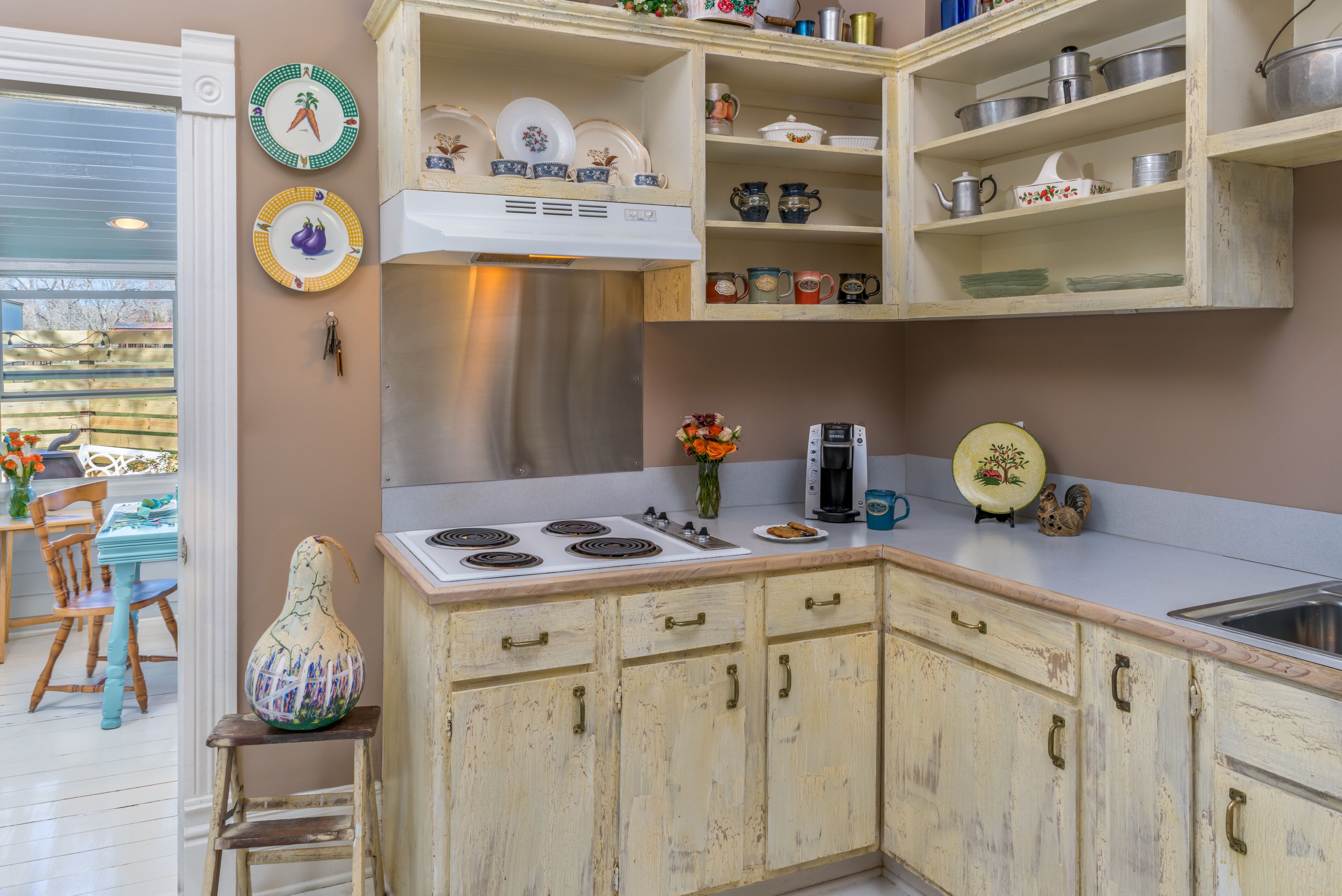 Una cocina con armarios de madera, estufa y diferentes platos y utensilios en estanterías.