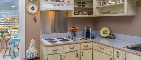 Una cocina con armarios de madera, estufa y diferentes platos y utensilios en estanterías.