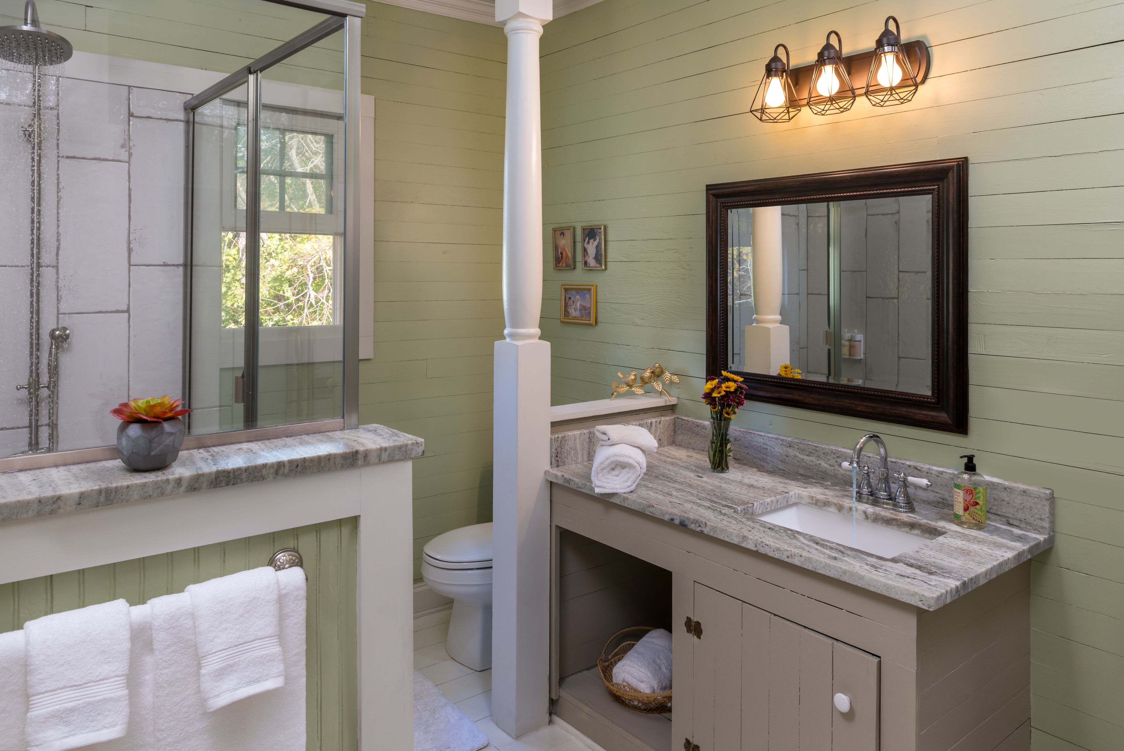 Un baño con ducha, lavabo, espejo y ventana.