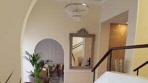Un hall amplio con piso de mármol, un espejo grande y una escalera con barandilla de madera.