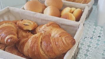 Un vassoio con diversi prodotti da forno, tra cui croissant e panini.