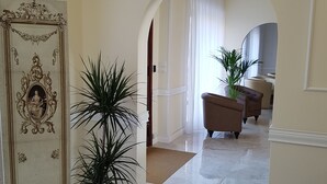 Un pasillo con piso de mármol, una puerta decorativa y plantas en macetas.