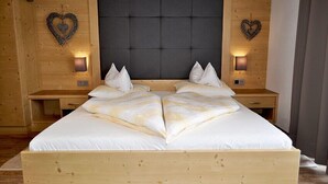 Una cama grande con estructura y cabecero de madera, flanqueada por dos mesitas de noche con lámparas.