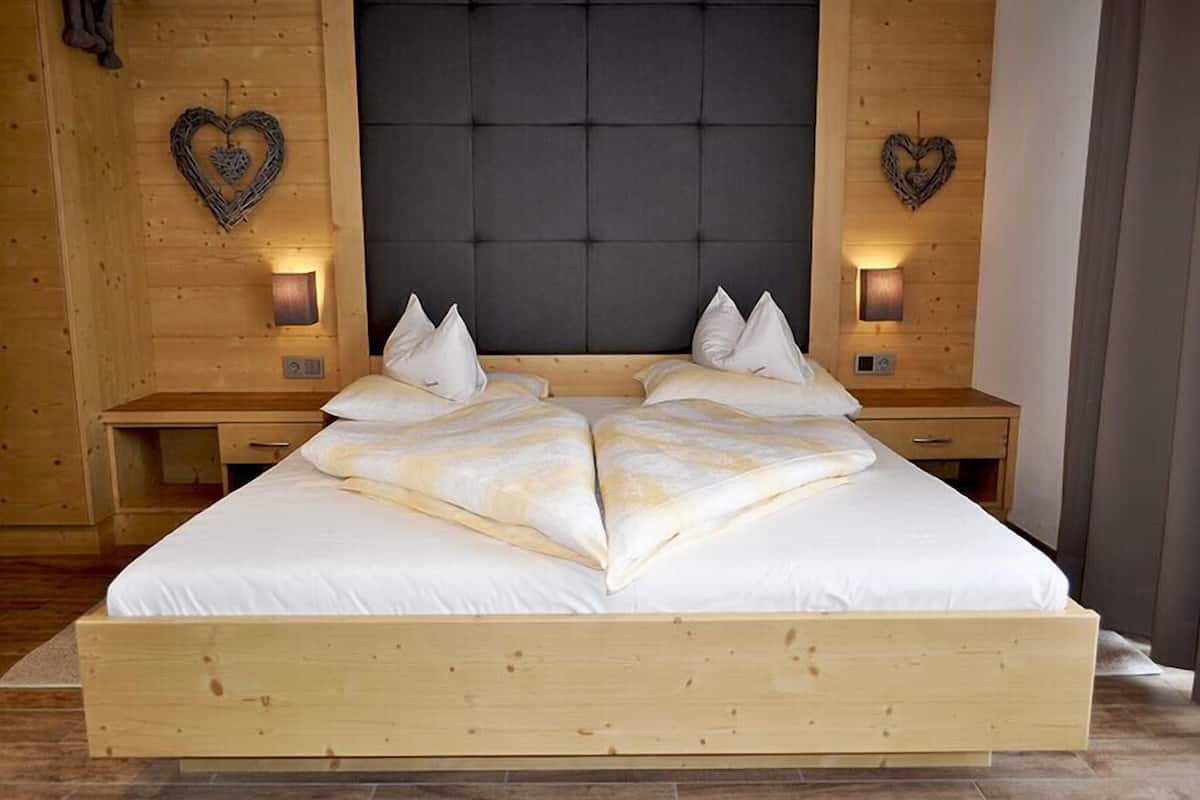 A large bed with a wooden frame and headboard, flanked by two bedside tables with lamps.