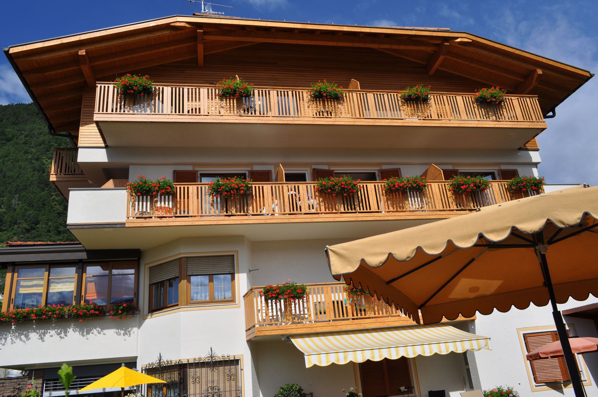 A multi-story building with wooden balconies, flower boxes, and outdoor seating areas.