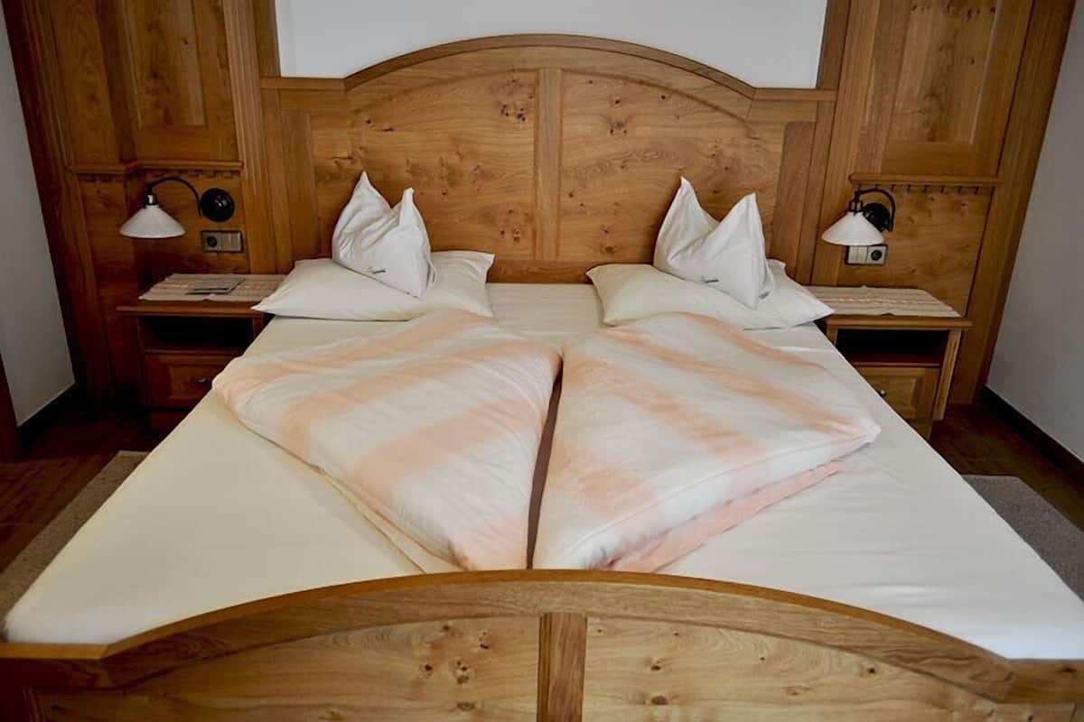 A double bed with a wooden headboard, two bedside tables with lamps, and a wooden wall paneling.