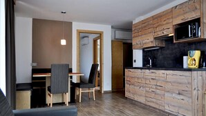 Un espacio habitable compacto con kitchenette, comedor y zona de estar.