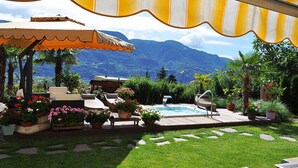 Un patio con mobiliario exterior, una piscina y vistas a montañas.