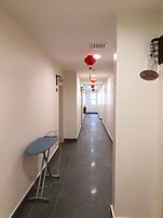 Ein sauberer, gut beleuchteter Flur mit einem blauen Bügelbrett, einem Feuerlöscher und einem Nummernschild '306' an der Wand.