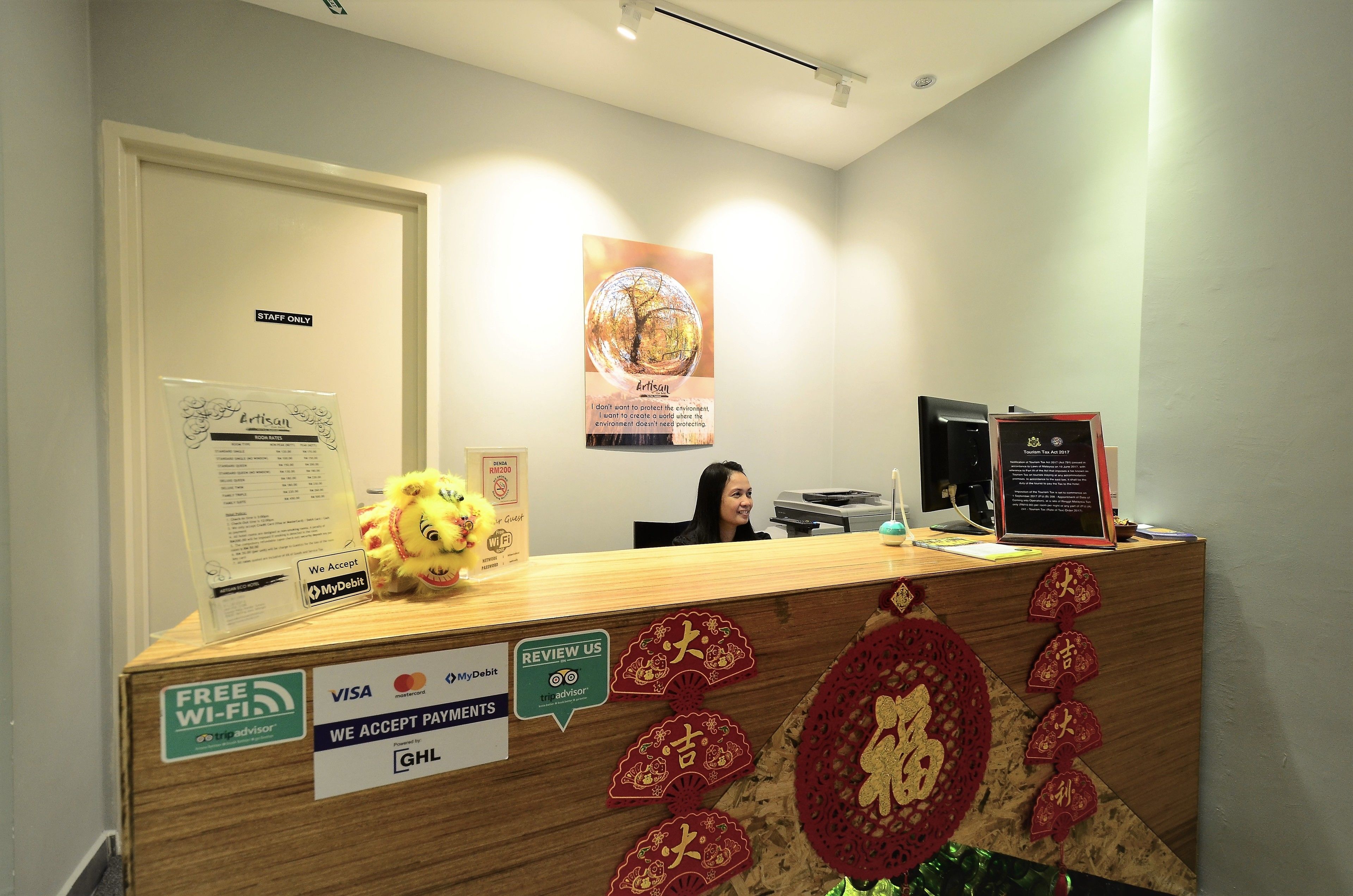 A reception desk with a 'Staff Only' sign, a plush toy, and various payment acceptance stickers.