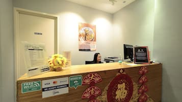 A reception desk with a 'Staff Only' sign, a plush toy, and various payment acceptance stickers.