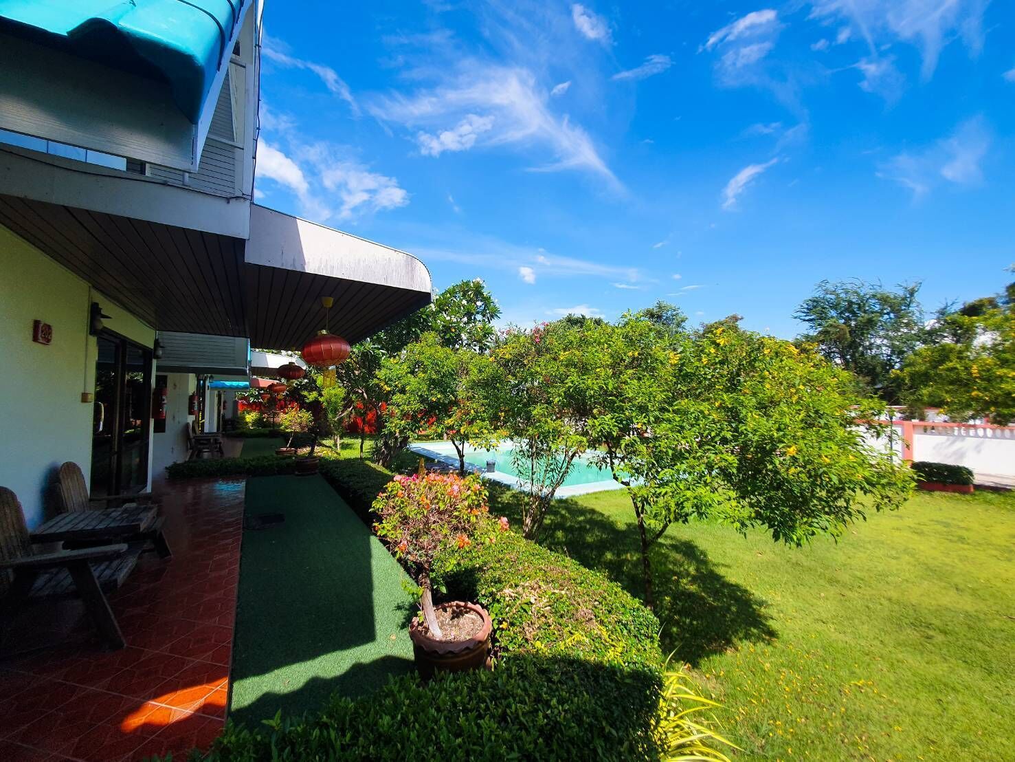 A hotel with a covered outdoor area, a swimming pool, and well-maintained greenery.