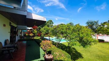 A hotel with a covered outdoor area, a swimming pool, and well-maintained greenery.