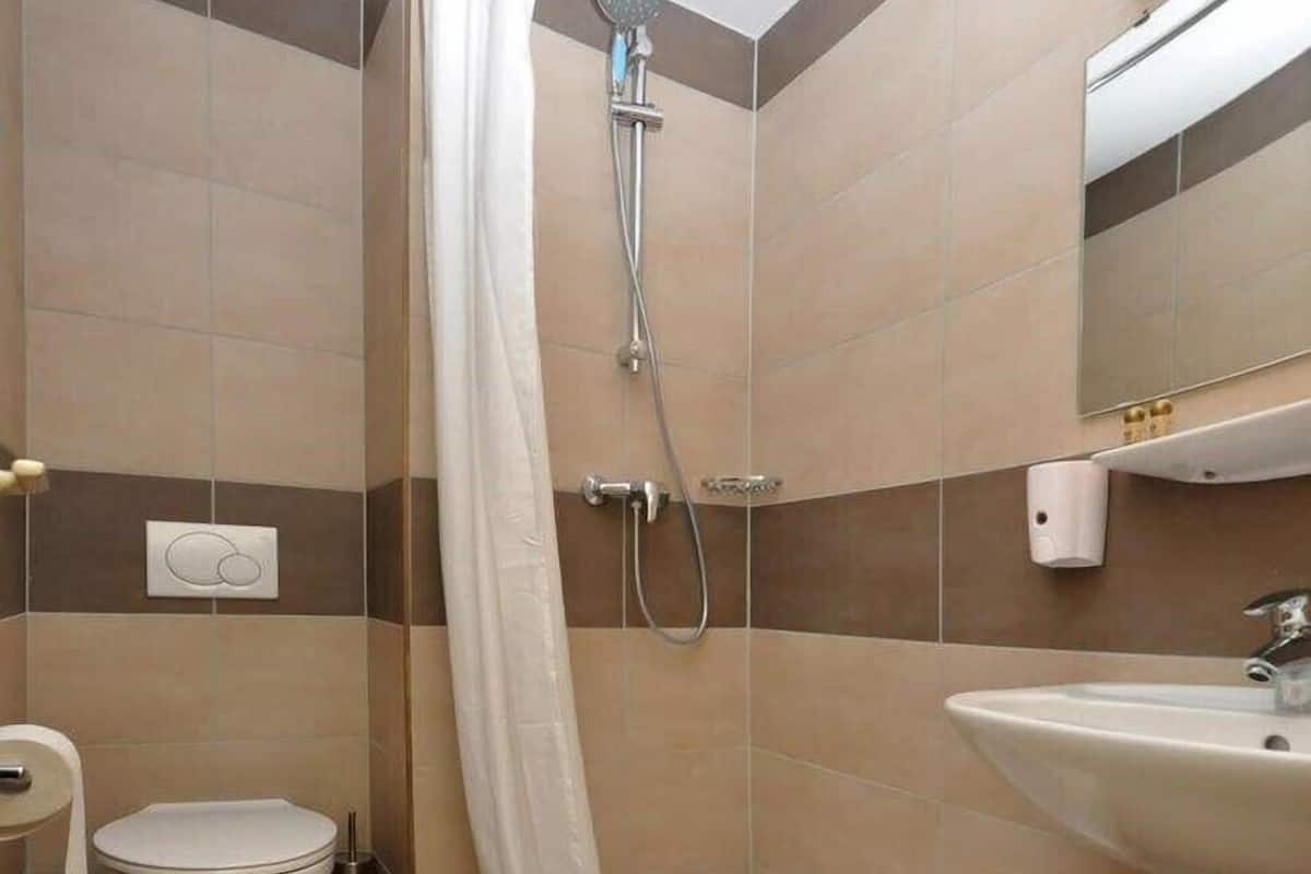 Um banheiro com chuveiro, vaso sanitário e pia.