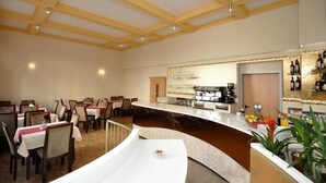 A restaurant with a curved counter, wooden ceiling beams, and a bar area with bottles. - Bova Hotel Frankfurt (Frankfurt)
