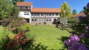 A traditional half-timbered building with a red-tiled roof, surrounded by a well-maintained lawn and flowering shrubs. - Gelpkes Muehle (Bad Sachsa)