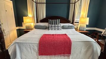 A bedroom with a large bed, two bedside tables with lamps, a wooden bench, and a patterned carpet.